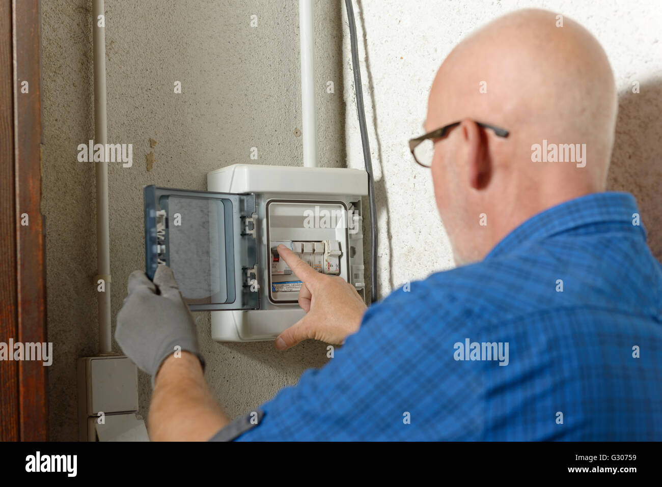 Un uomo maturo lavora con scatola elettrica a casa Foto Stock