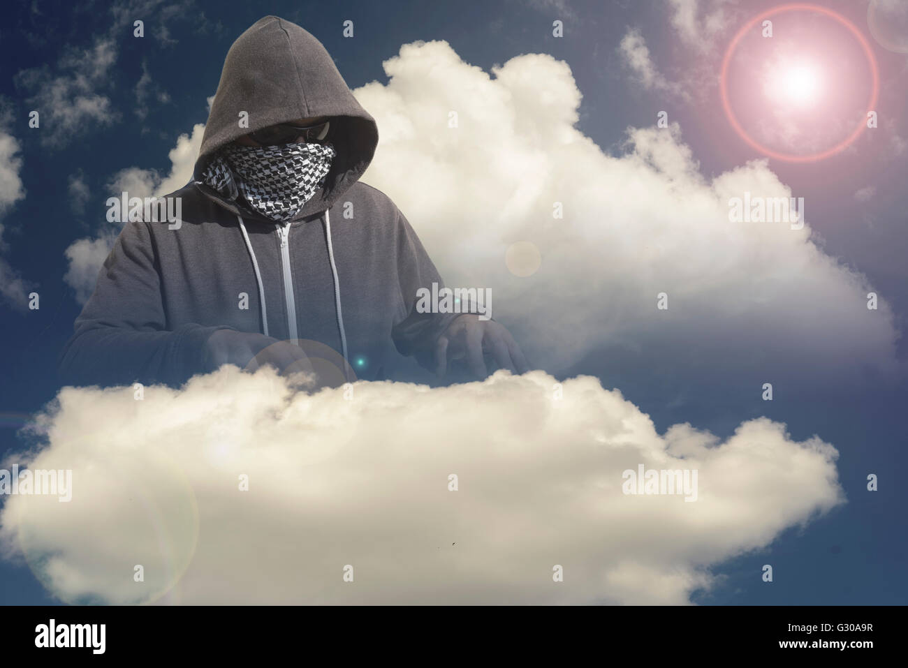 Incappucciato e mascherato hacker ladro con un computer cloud basato sullo sfondo. Tecnologia sconosciuta minaccia per il mainframe cloud Foto Stock