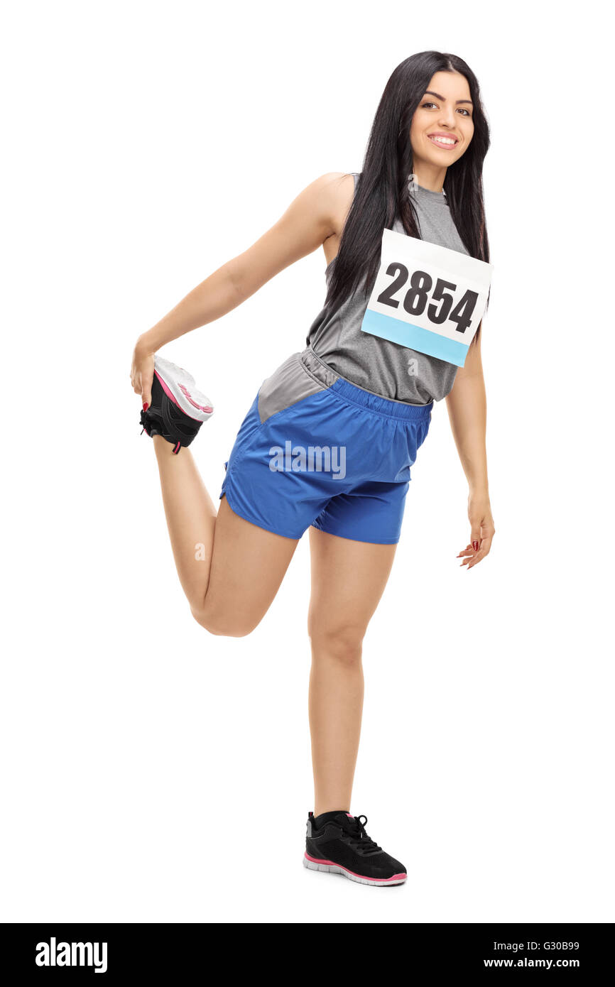 A piena lunghezza Ritratto di una donna allegra maratoneta stretching le sue gambe e preparazione di una gara Foto Stock