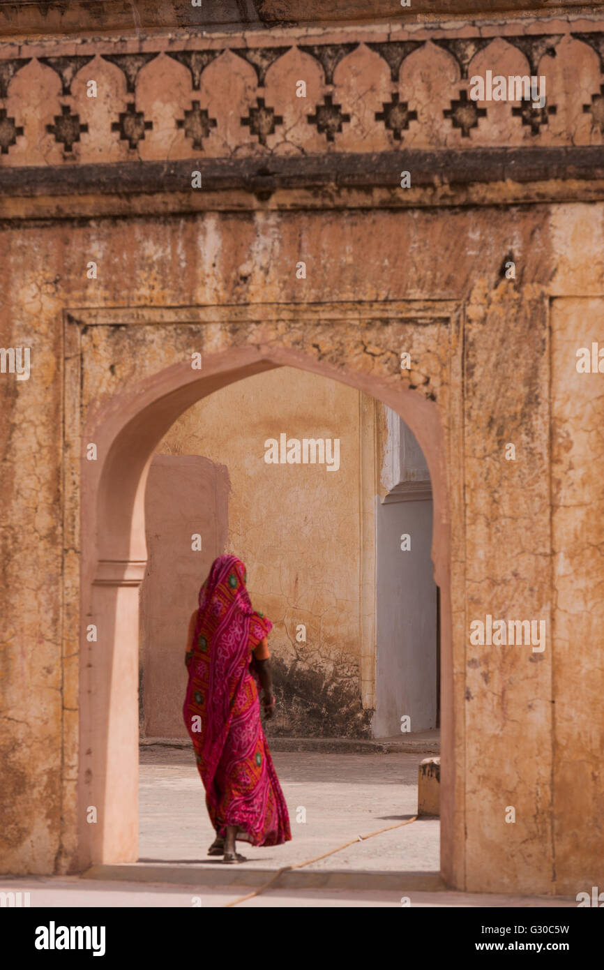 Signora in abito tradizionale a piedi attraverso un gateway in Forte Amber vicino a Jaipur, Rajasthan, India, Asia Foto Stock