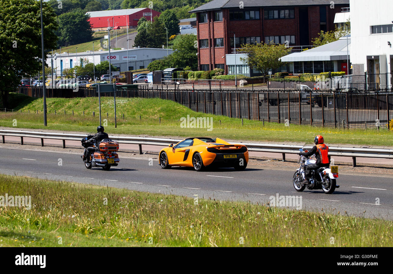 Una McLaren MP4-12C Spider convertibile auto sportive il sorpasso di due motociclette lungo il Kingsway West a doppia carreggiata a Dundee, Regno Unito Foto Stock