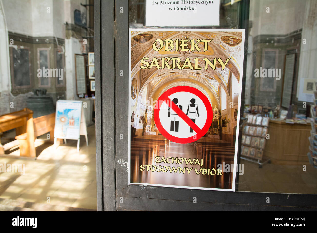 Poster sul display all'entrata di una chiesa cattolica a Danzica chiedendo ai visitatori di vestire appropriatamente, Polonia, Europa Foto Stock