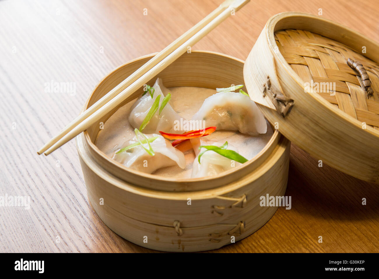 Dim somme con gamberetti in un sistema per la cottura a vapore in bambù su una tavola di legno nel ristorante asiatico Foto Stock