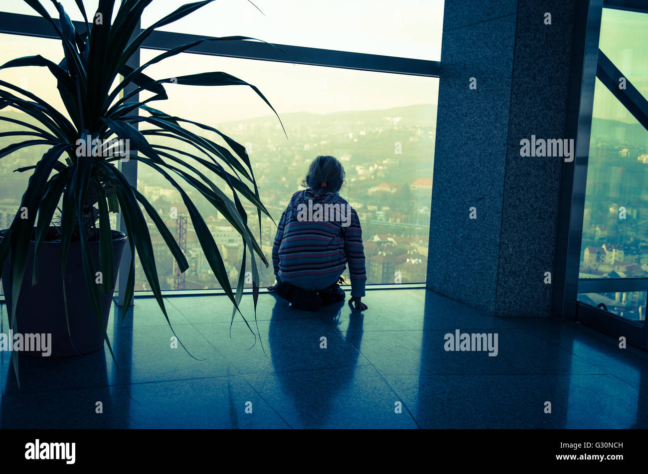 Bambino di guardare attraverso una finestra per la città Foto Stock