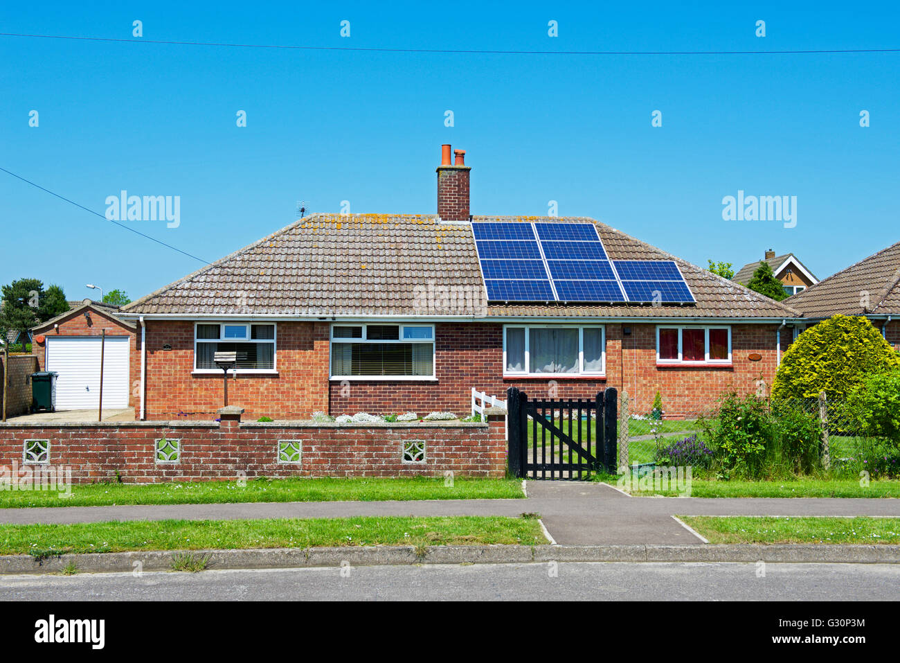 Semi-detached bungalow, metà del tetto con pannelli solari, metà senza, England Regno Unito Foto Stock