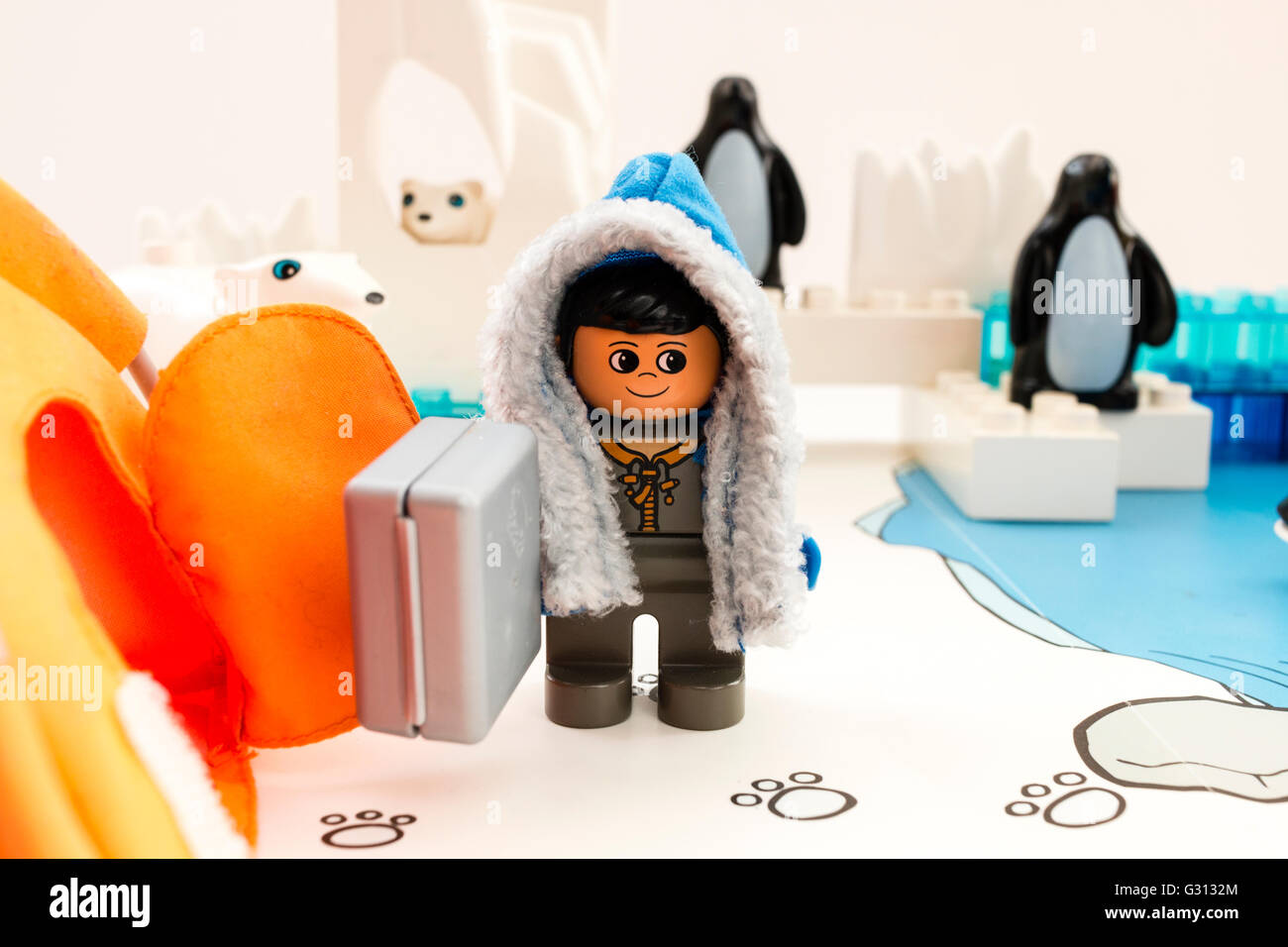 Lego Duplo esplorare Arctic playset. Lego figura indossa cappotto invernale e valigetta al campo base. Iceberg, pinguini e orso polare in background. Foto Stock