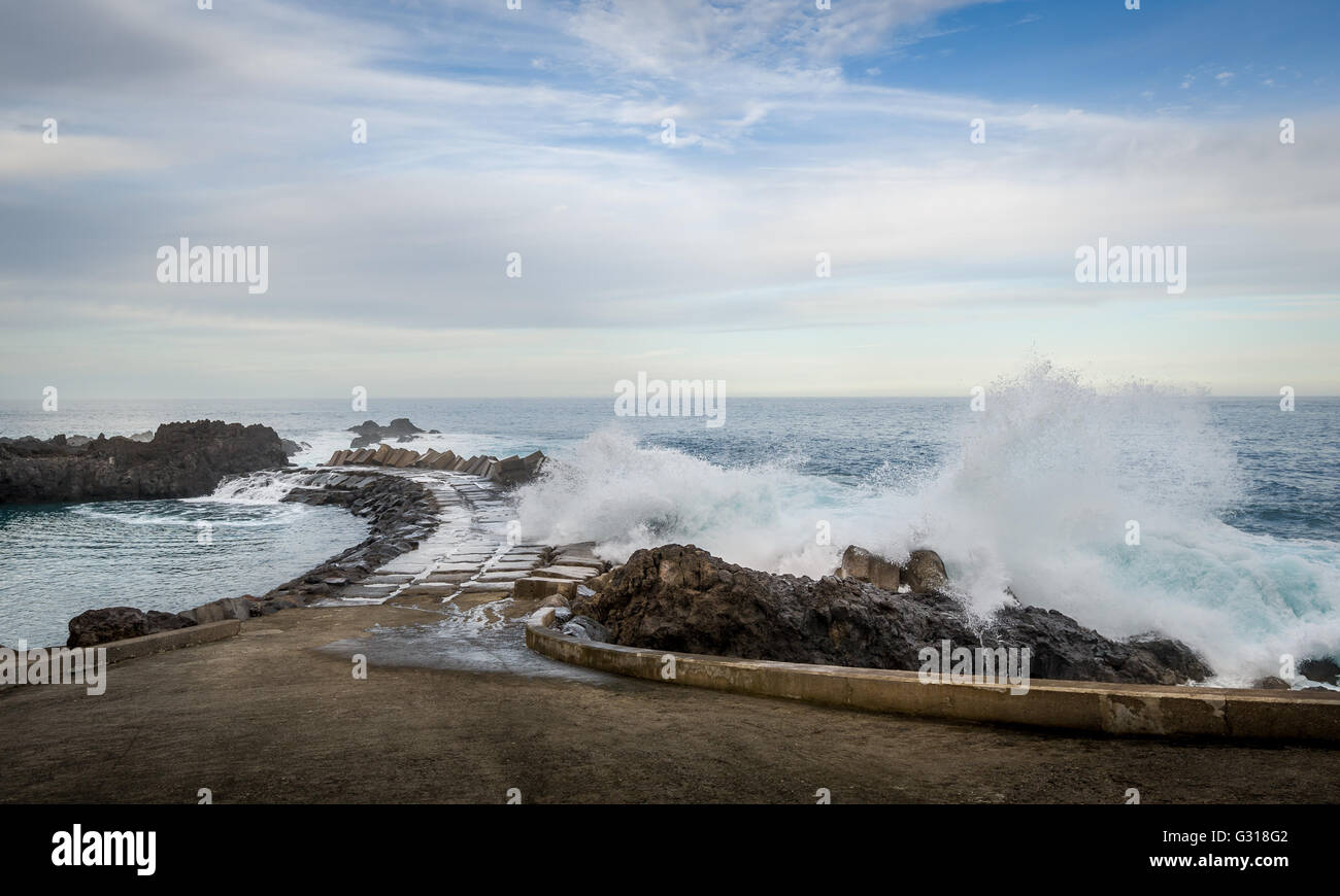 Spruzzi delle onde del molo per l'Oceano Atlantico a Seixal, isola di Madeira Foto Stock