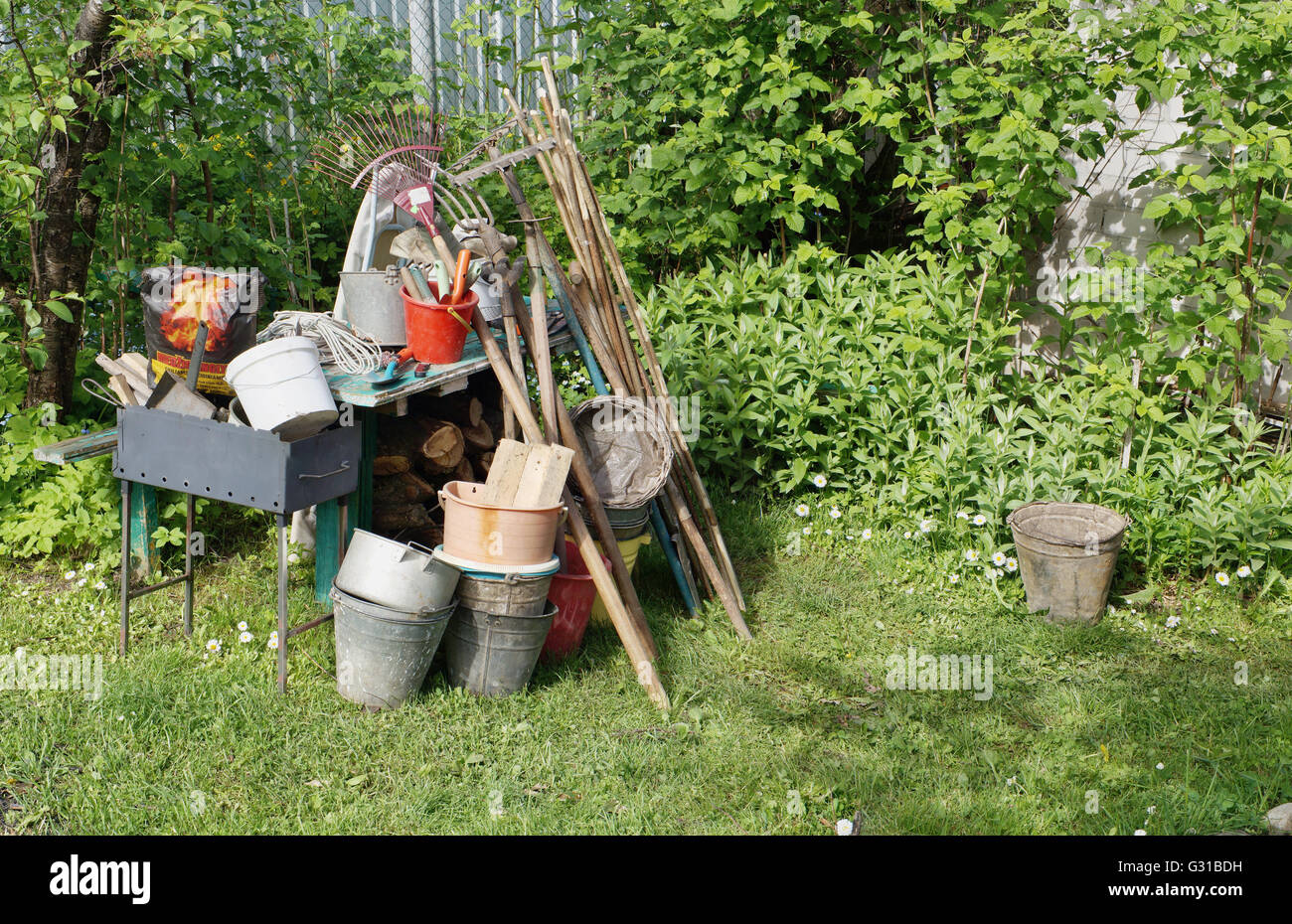 Il rurale utilizzati utensili per la lavorazione della terra e di lotta contro le erbe infestanti. Un braciere per un barbecue e un pacchetto di carbone. Un ins Foto Stock