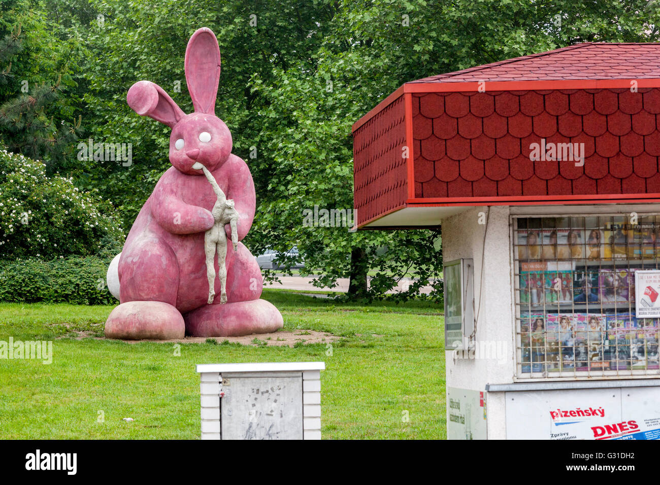 Statua di un coniglio rosa che mangia umano, scultura in cemento sulla proprietà immobiliare Pilsen Repubblica Ceca animale arte scena di strada, coniglio città di strada Foto Stock