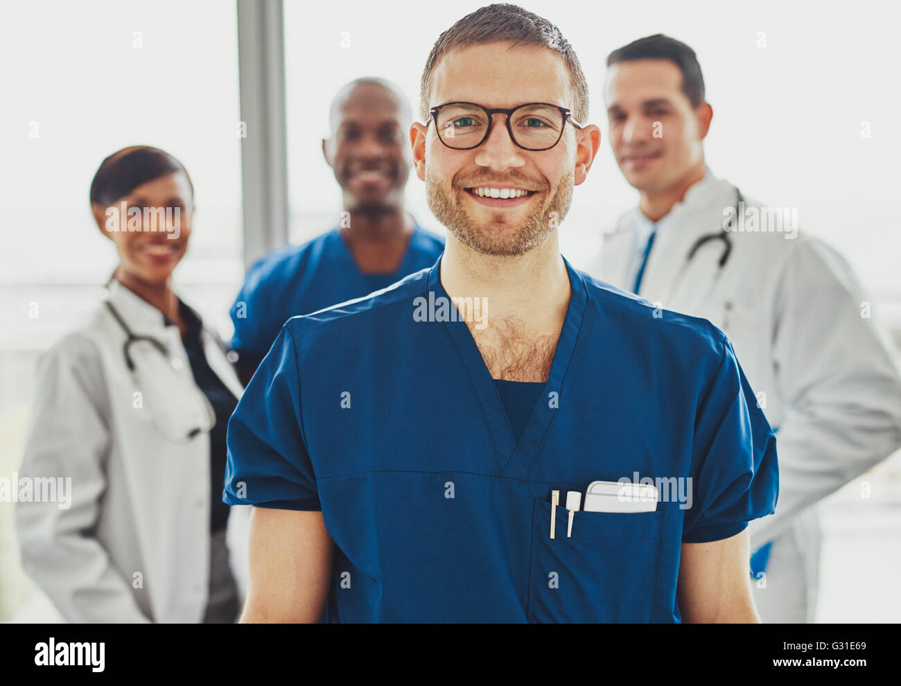 Medico leader del team medico all'ospedale, sorridente rilassata in telecamera, chirurgo vestiti Foto Stock