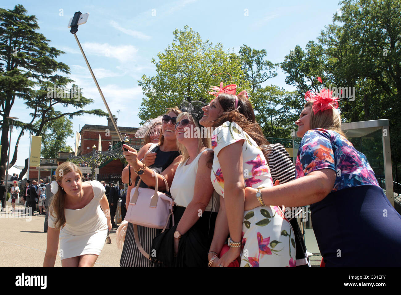Ascot, Regno Unito, elegantemente vestito le donne di scattare una foto utilizzando una Selfie bastoni Foto Stock