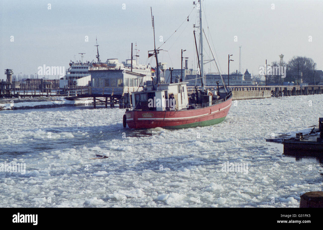 Warnemuende, DDR, barca da pesca si trova sull'Alter Strom bloccato nel ghiaccio Foto Stock