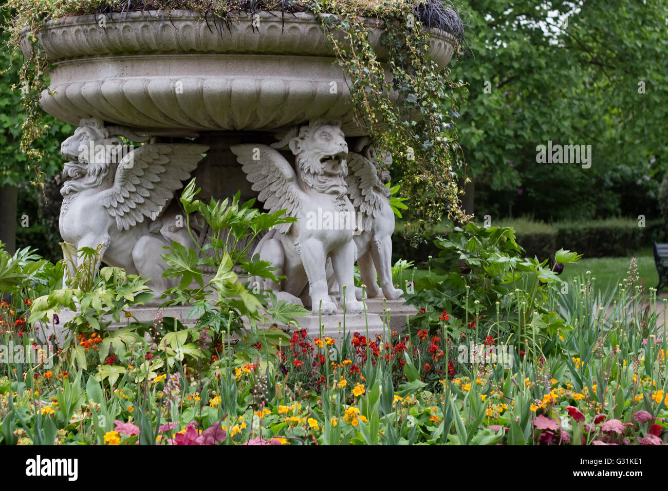Londra, Inghilterra - 19 Maggio 2016: Stone leoni alati tra fiori in Regent's Park di Londra, Inghilterra. Foto Stock