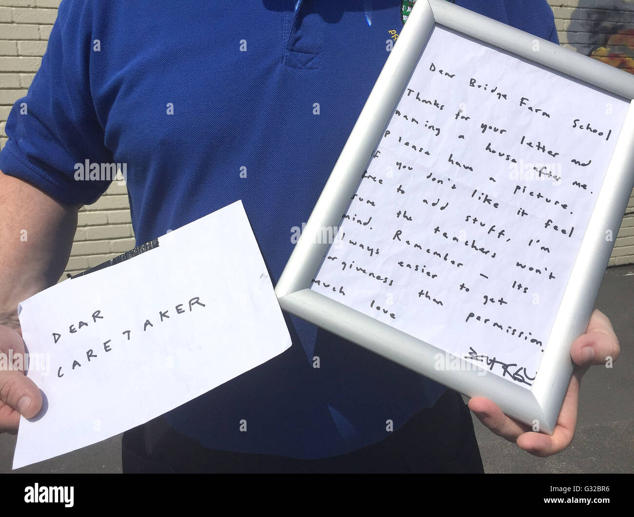 Site Manager Jason Brady tenendo una lettera a sinistra da Banksy al Bridge Farm primario nel Bristol dopo dipinse un murale sul lato di una delle aule durante il semi-termine. Foto Stock