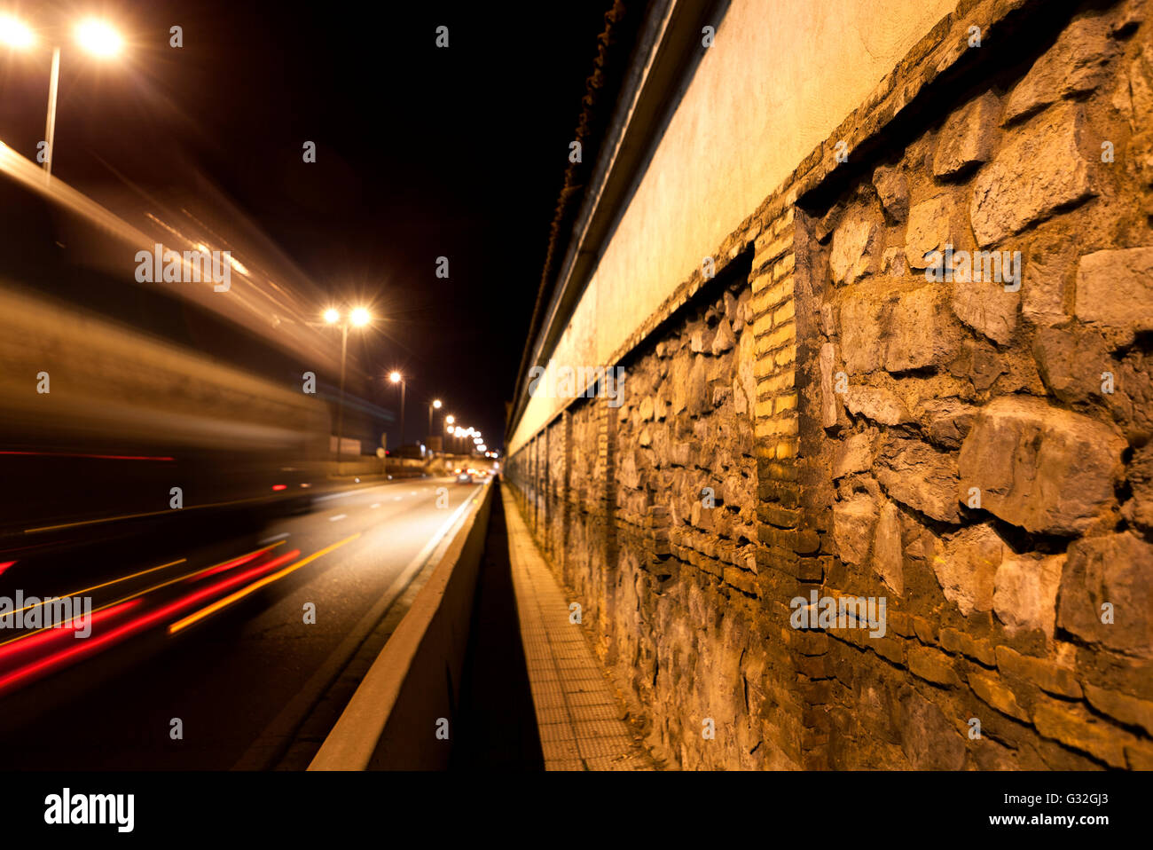 Strada di città di notte.parete di ciottoli e strada Foto Stock