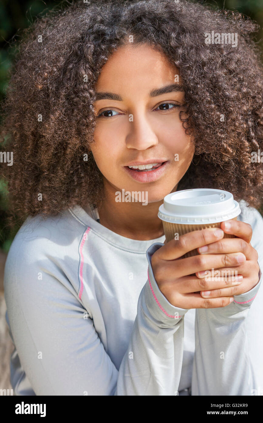 Bella felice razza mista americano africano ragazza adolescente femmine giovane donna sorridente a bere il caffè da asporto al di fuori Foto Stock
