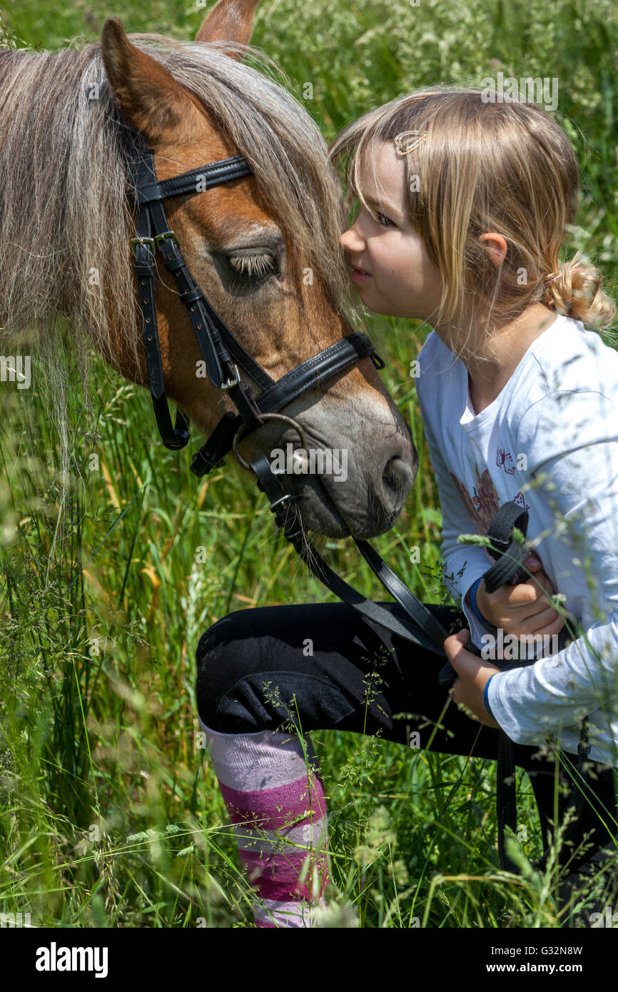 6 anni, bambina con il pony in un prato estivo, carezza di pony del bambino, carezzatura Foto Stock