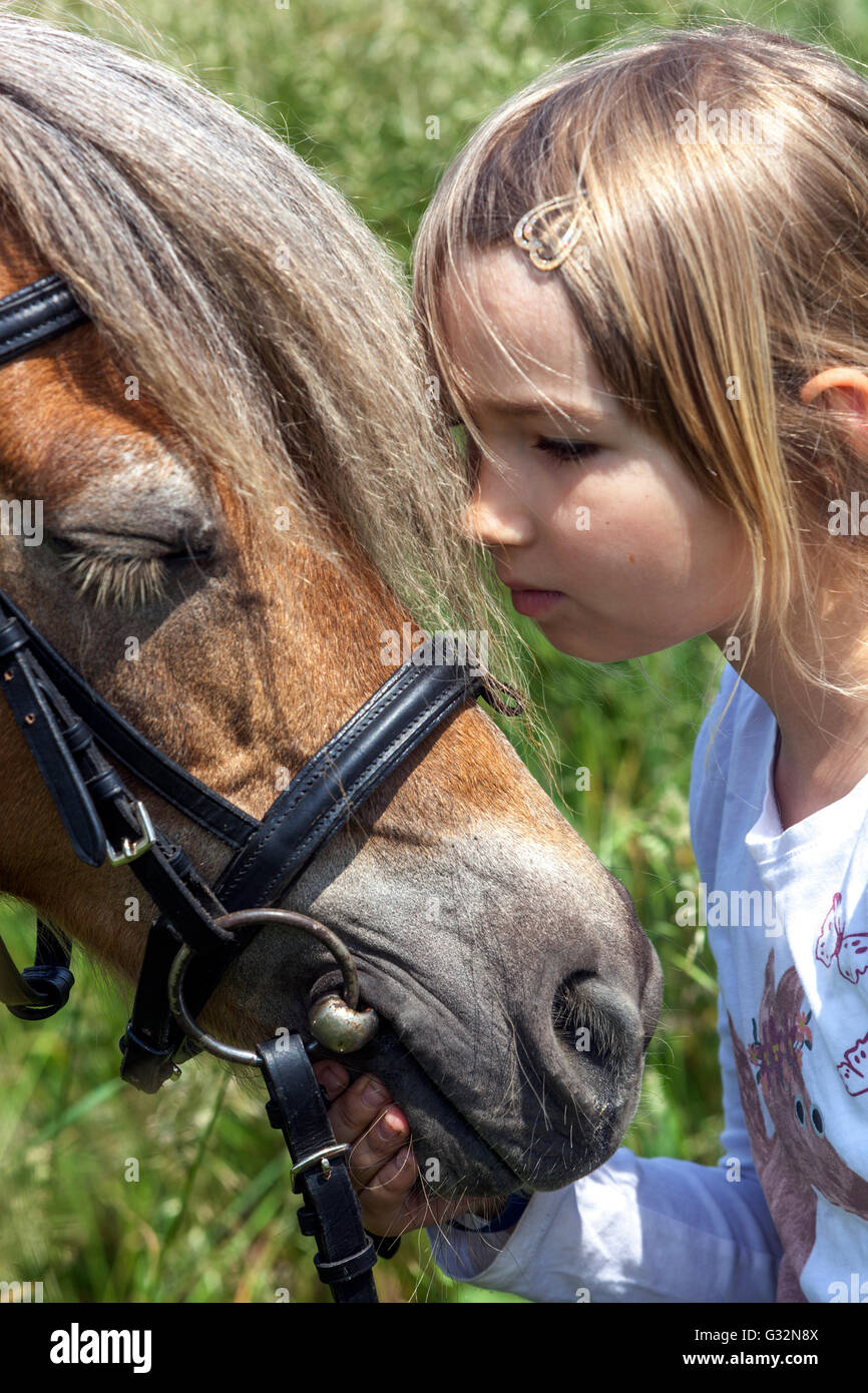 Bambino di 6 anni, bambina con pony, pony carezzante Foto Stock