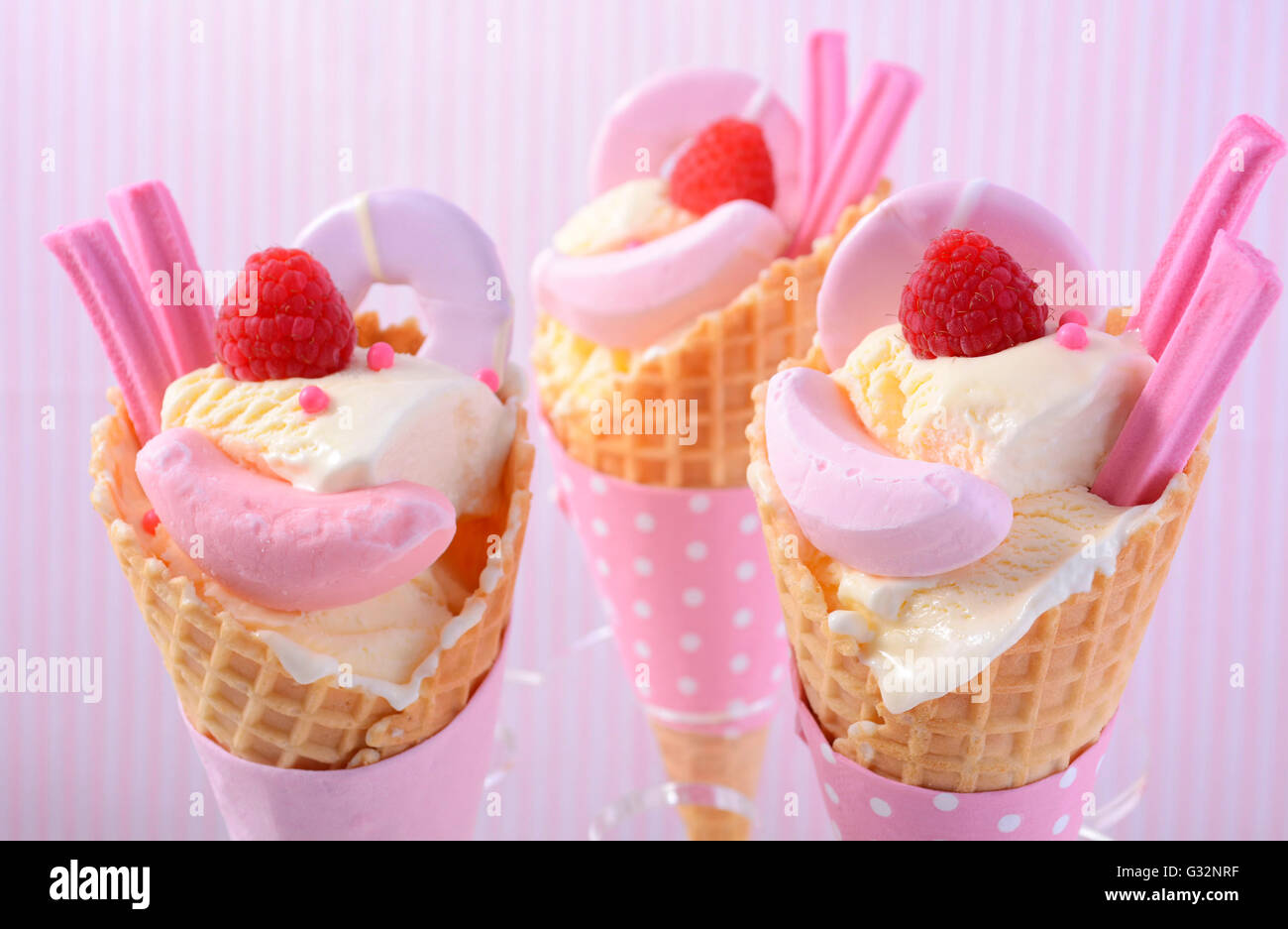 È arrivata l'estate themed vaniglia gelati in coni con rosa candy decorazioni su striscia rosa sfondo. Foto Stock