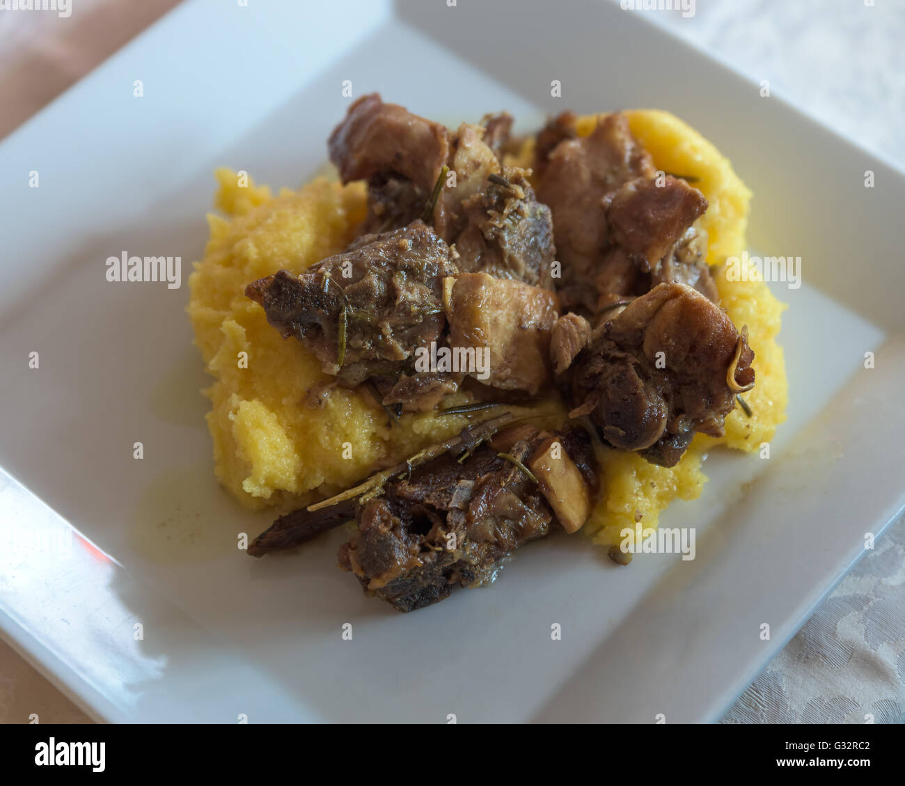 Nella foto prodotti tipici italiani ,arrosto di capra e la polenta sul piatto bianco al ristorante,vista dall'alto. Foto Stock