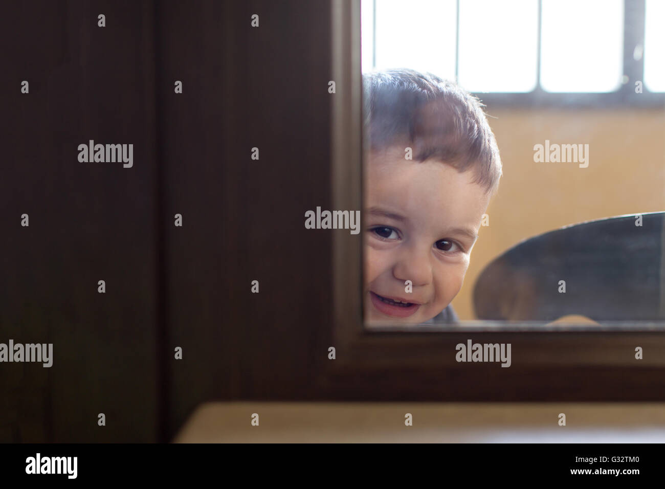 Ritratto di un ragazzo di guardare attraverso una finestra Foto Stock
