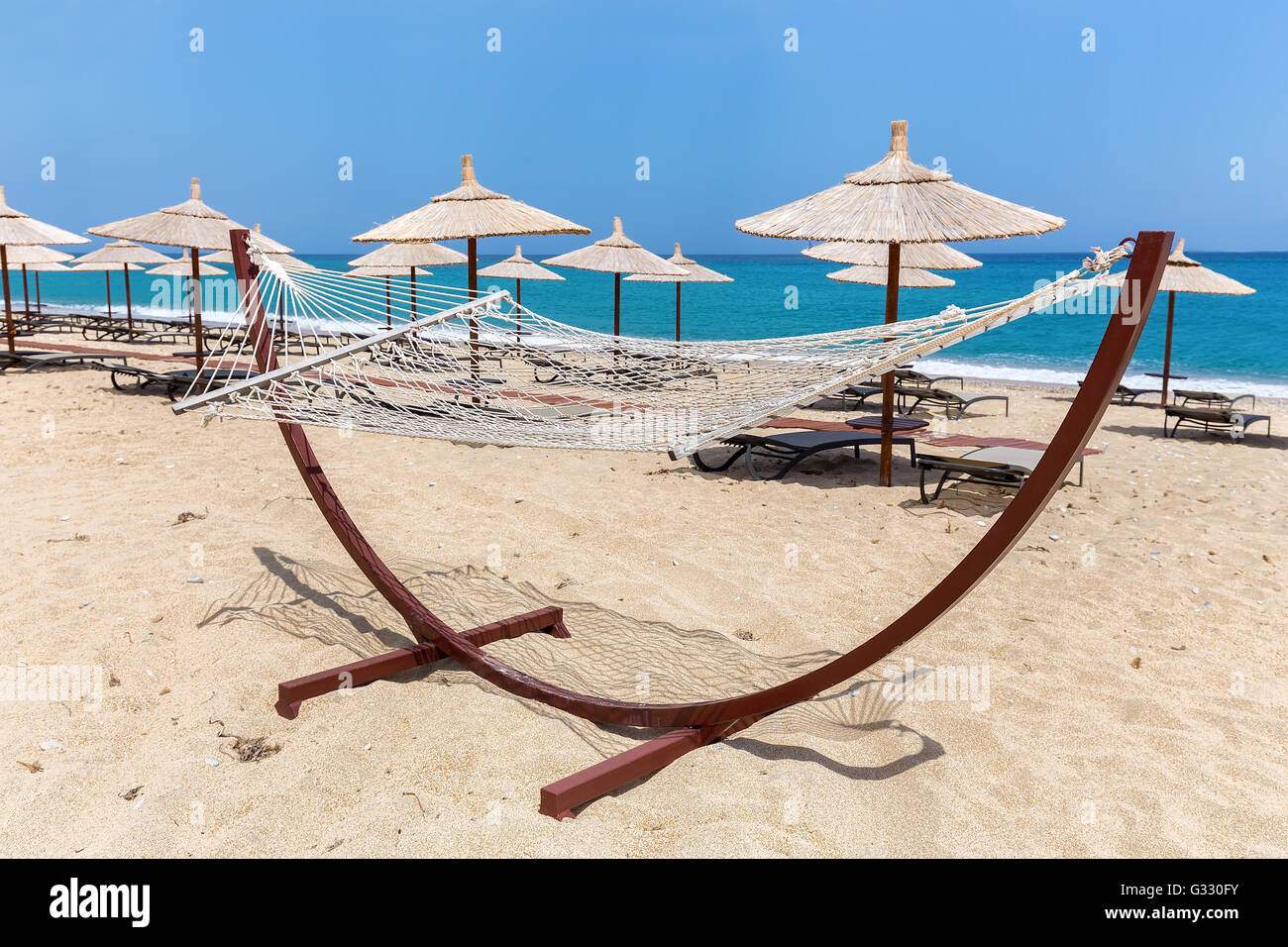 Amaca con ombrelloni e lettini a costa greca con vista mare Foto Stock