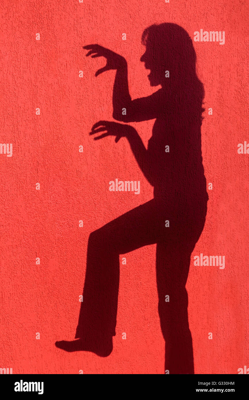 Profilo ombra silhouette di donna arrabbiato sulla parete rossa Foto Stock