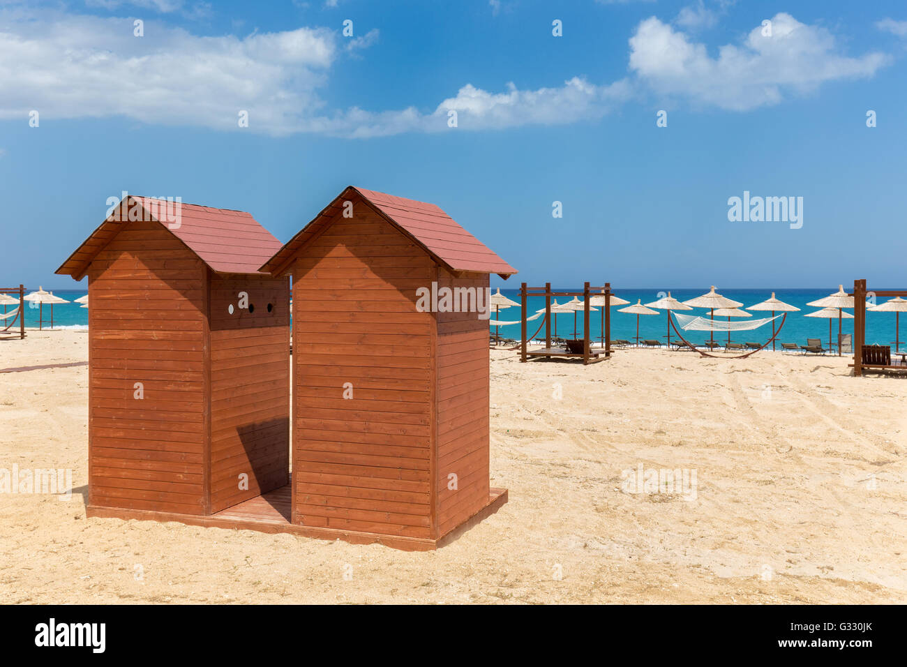 Due cabine in legno con ombrelloni sulla riva sabbiosa in Grecia Foto Stock
