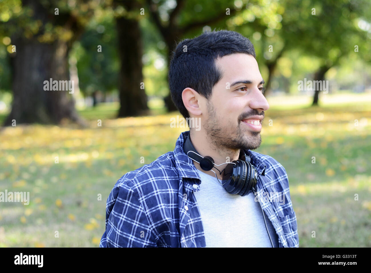Chiusura del giovane uomo bello con le cuffie in un parco. All'esterno. Foto Stock