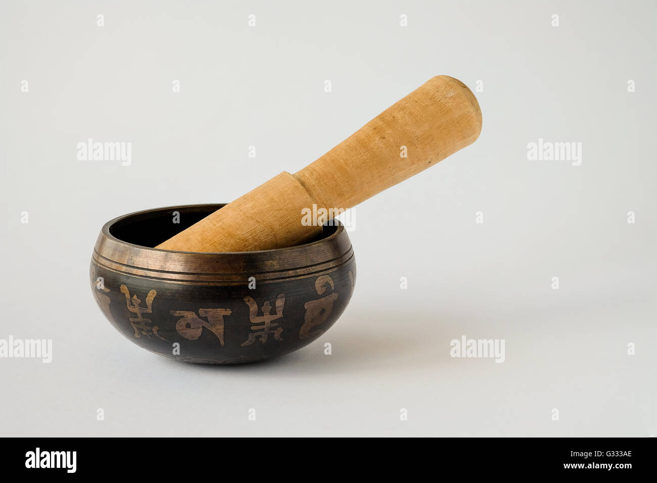 Bronzo decorativo Tibetan Singing Bowl con un mazzuolo di legno. Ogni secondo simbolo è un carattere tibetano che compongono il mantra "om Foto Stock