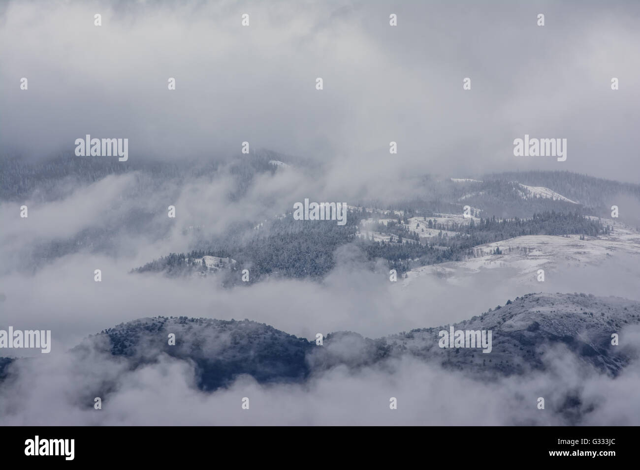 Nuvole scendendo su una montagna innevata. Foto Stock