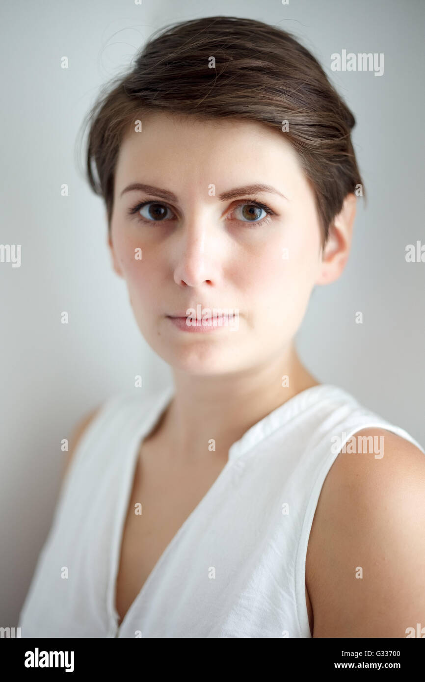 Affascinante di capelli corti giovane donna senza trucco su sfondo bianco Foto Stock