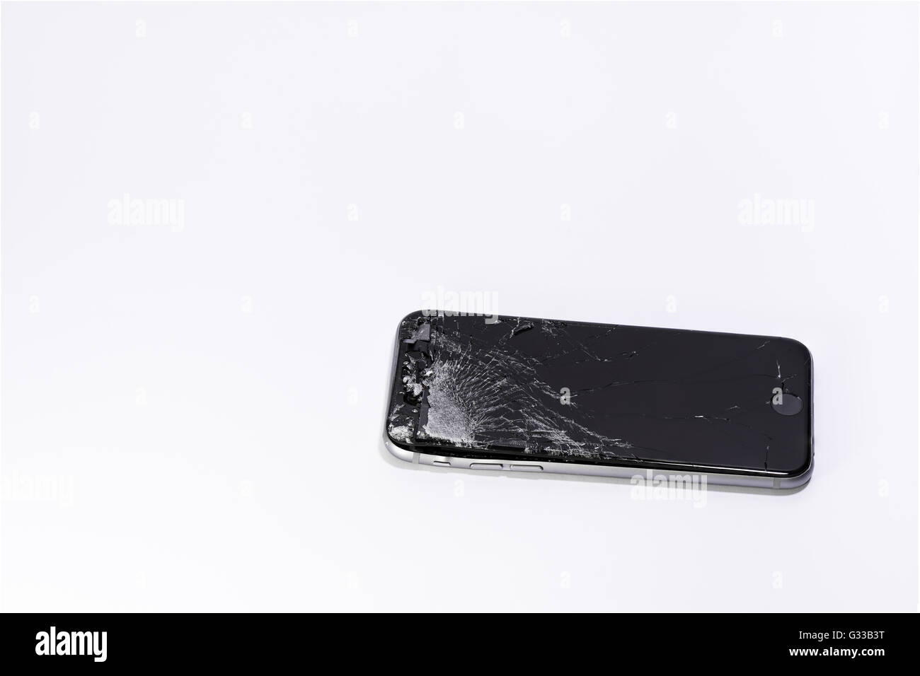 Un telefono cellulare con schermo rotto su sfondo bianco Foto Stock