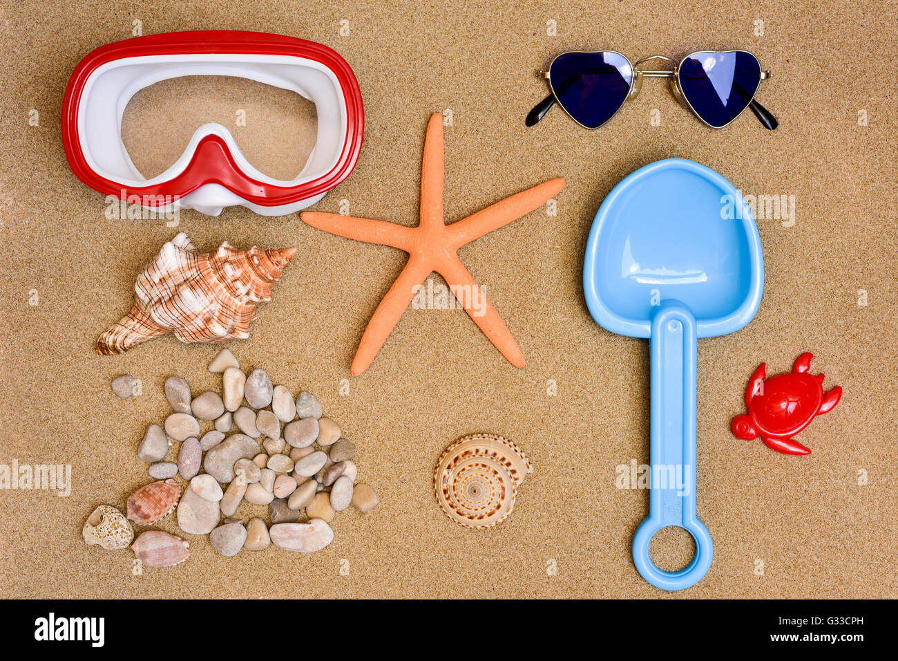 Alta angolazione di alcune cose di estate, ad una maschera subacquea, una stella di mare, una coppia di a forma di cuore occhiali da sole, un giocattolo pala, alcuni conc Foto Stock