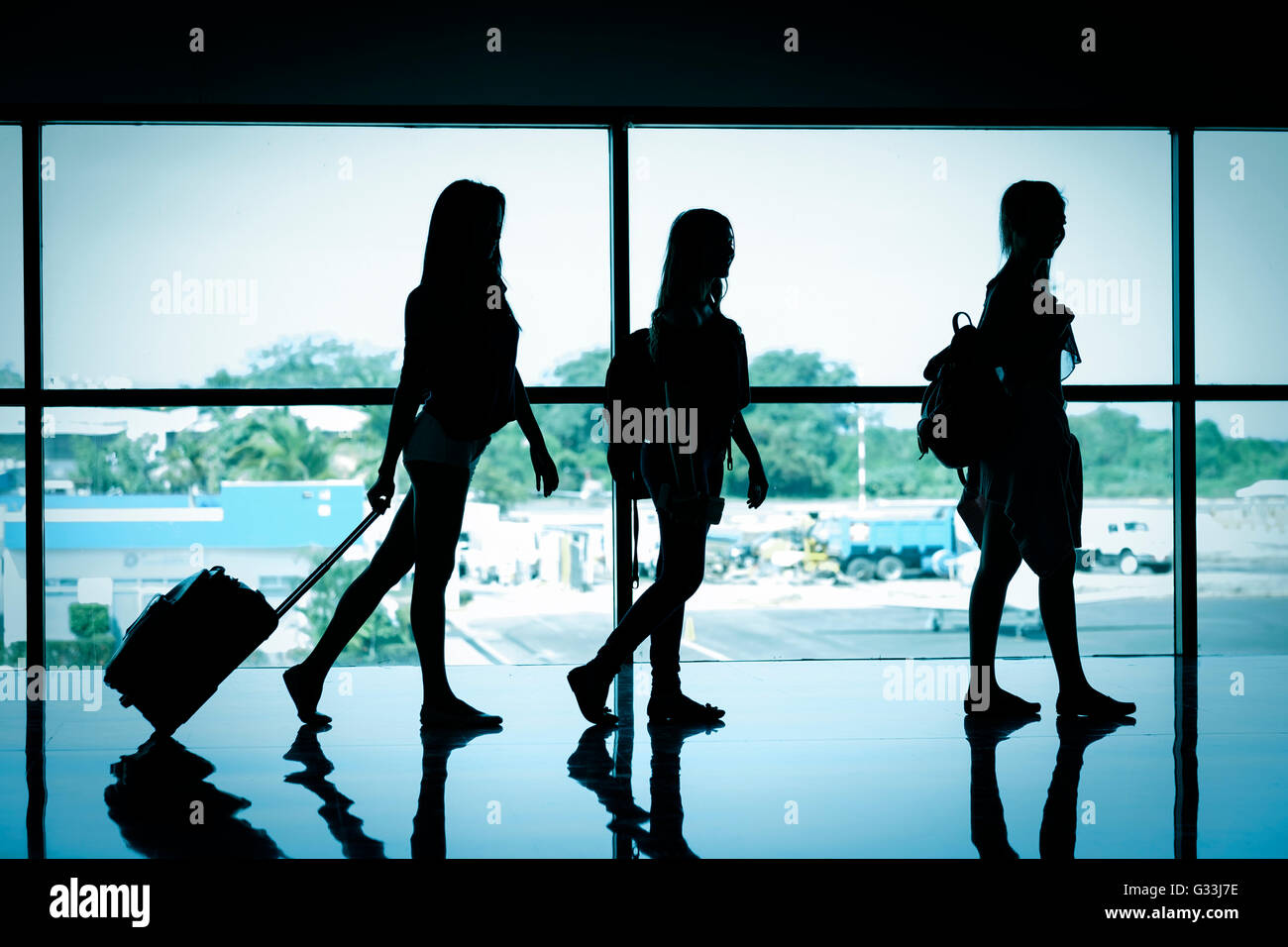 Silhouette di 3 viaggiatori femmina al terminal aeroportuale Foto Stock