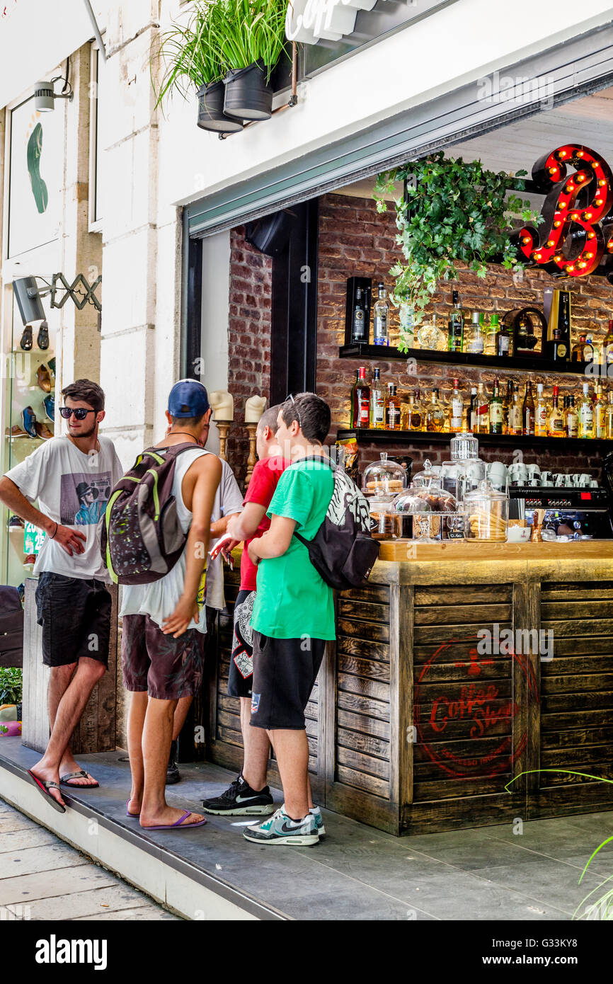 Casualmente vestito giovani uomini stavano in piedi presso un Bar, Corfù Città vecchia di Corfù, Grecia Foto Stock