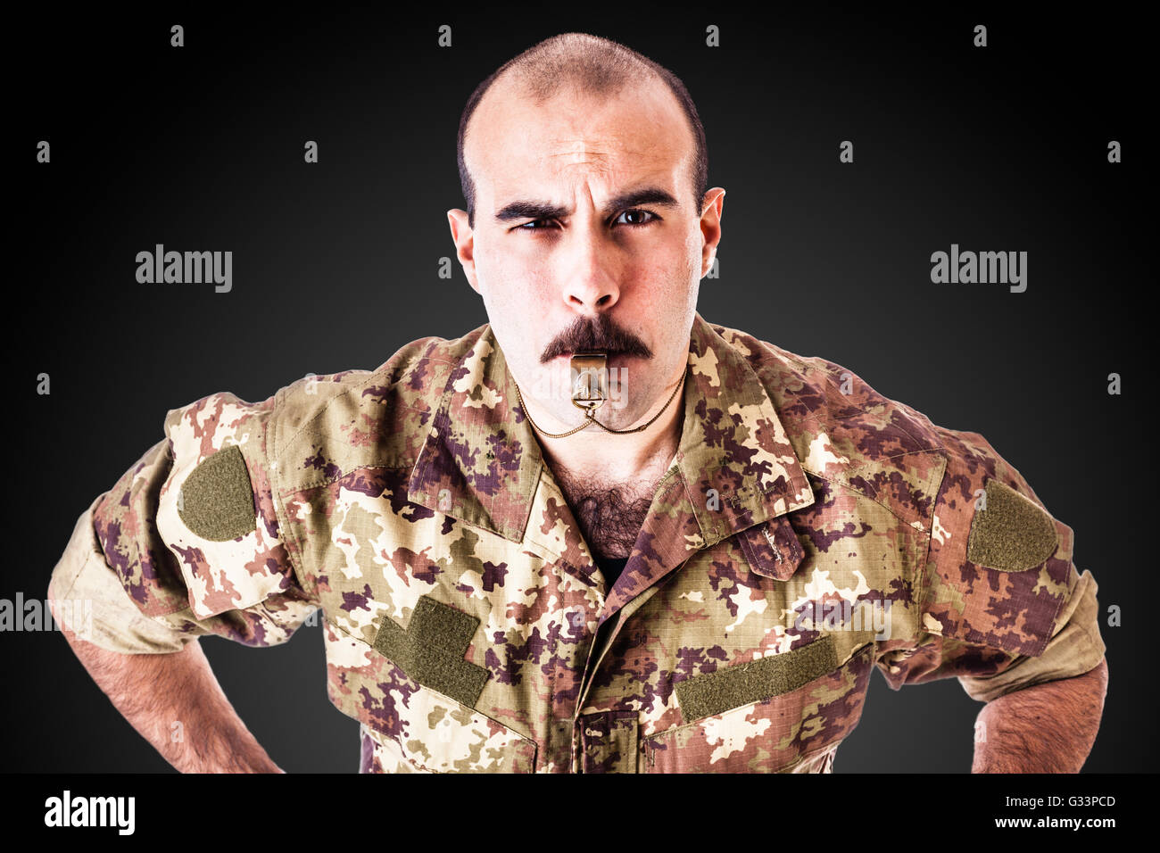 Un soldato o praticare il sergente soffia un fischio su uno sfondo scuro Foto Stock