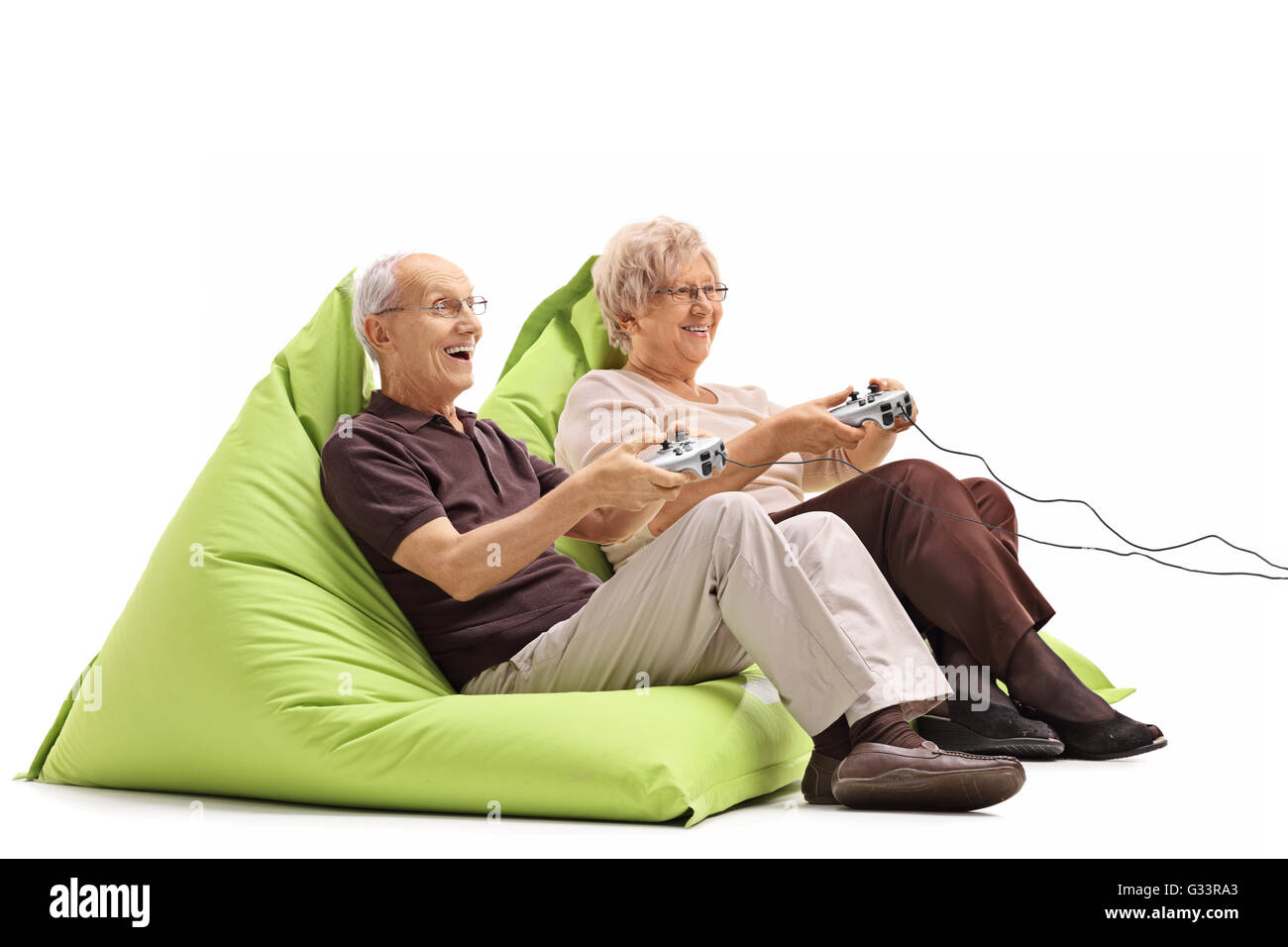 Coppia di anziani la riproduzione di video giochi seduto sul verde beanbags isolati su sfondo bianco Foto Stock