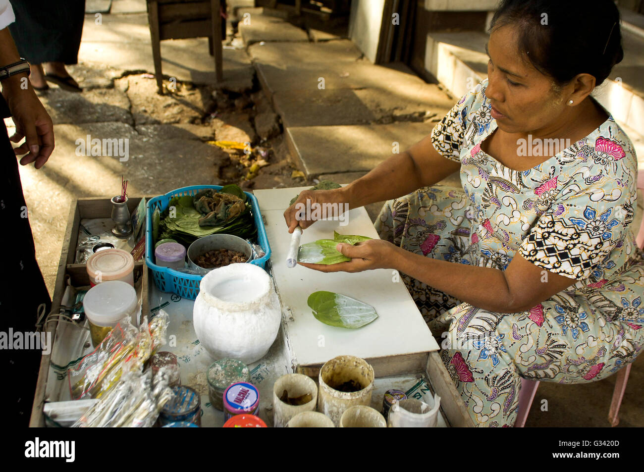 Un fornitore paan preparare una miscela di tabacco e noci di arec dado su una foglia di betel. Foto Stock