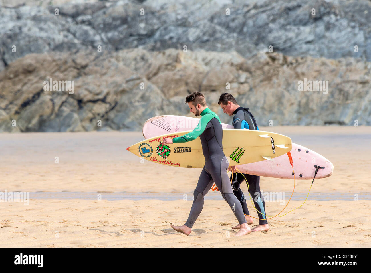 Due surfisti passeggiate a mare a Fistral in Newquay, Cornwall. Foto Stock