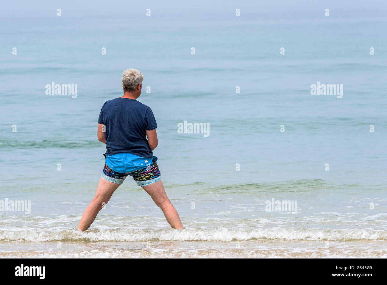Un uomo con una strana posizione al Fistral Beach in Newquay, Cornwall. Foto Stock