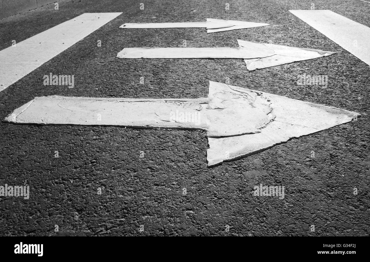 Frecce di colore bianco su nero autostrada asfalto, attraversamento pedonale strada frammento di marcatura Foto Stock