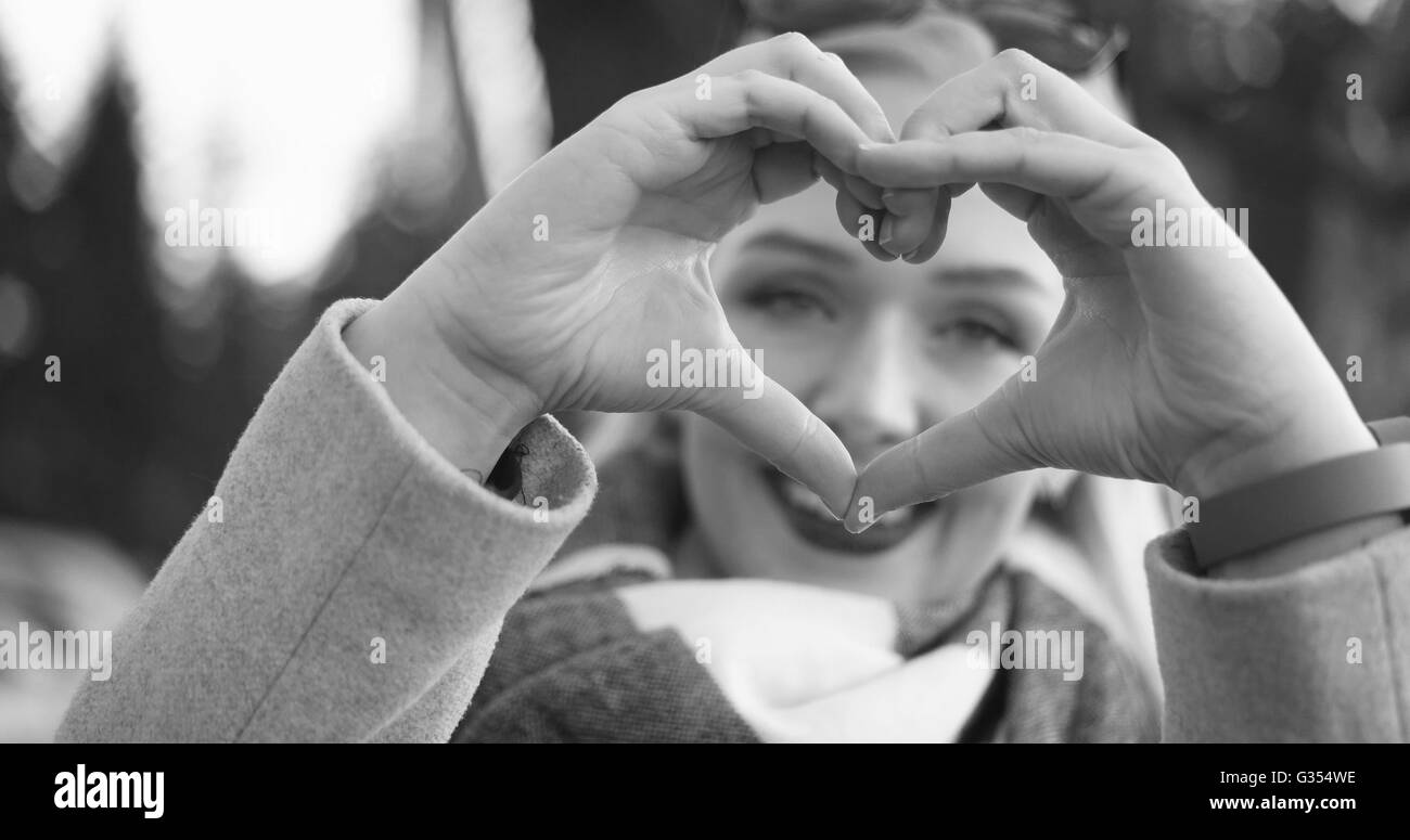Caucasico bella donna bionda che mostra segni di cuore con le dita, il giorno di san valentino concetto amore Foto Stock