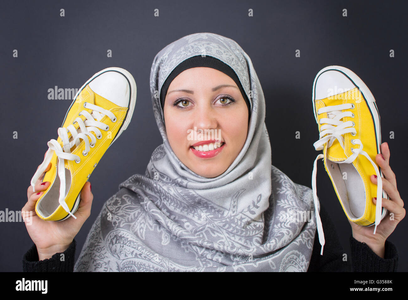 Donna musulmana holding sneakers giallo Foto Stock