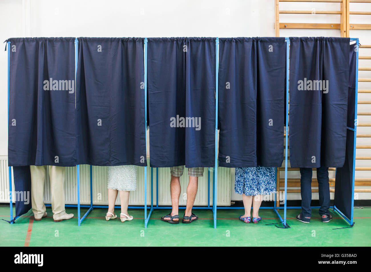 Immagine a colori di alcune persone voto in alcune cabine di polling in corrispondenza di una stazione di voto. Foto Stock