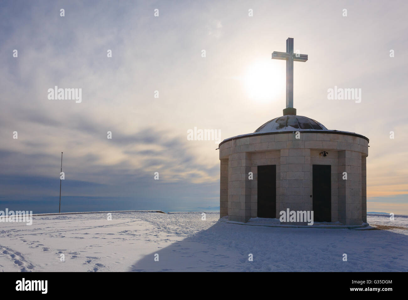 Cristian croce su di una piccola chiesa con Sun in controluce. Italiano panorama invernale Foto Stock