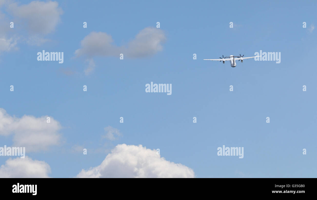Bianco di " commuters " Compagnia aerea aereo in fase di decollo in un cielo blu con il bianco puffy nuvole Foto Stock