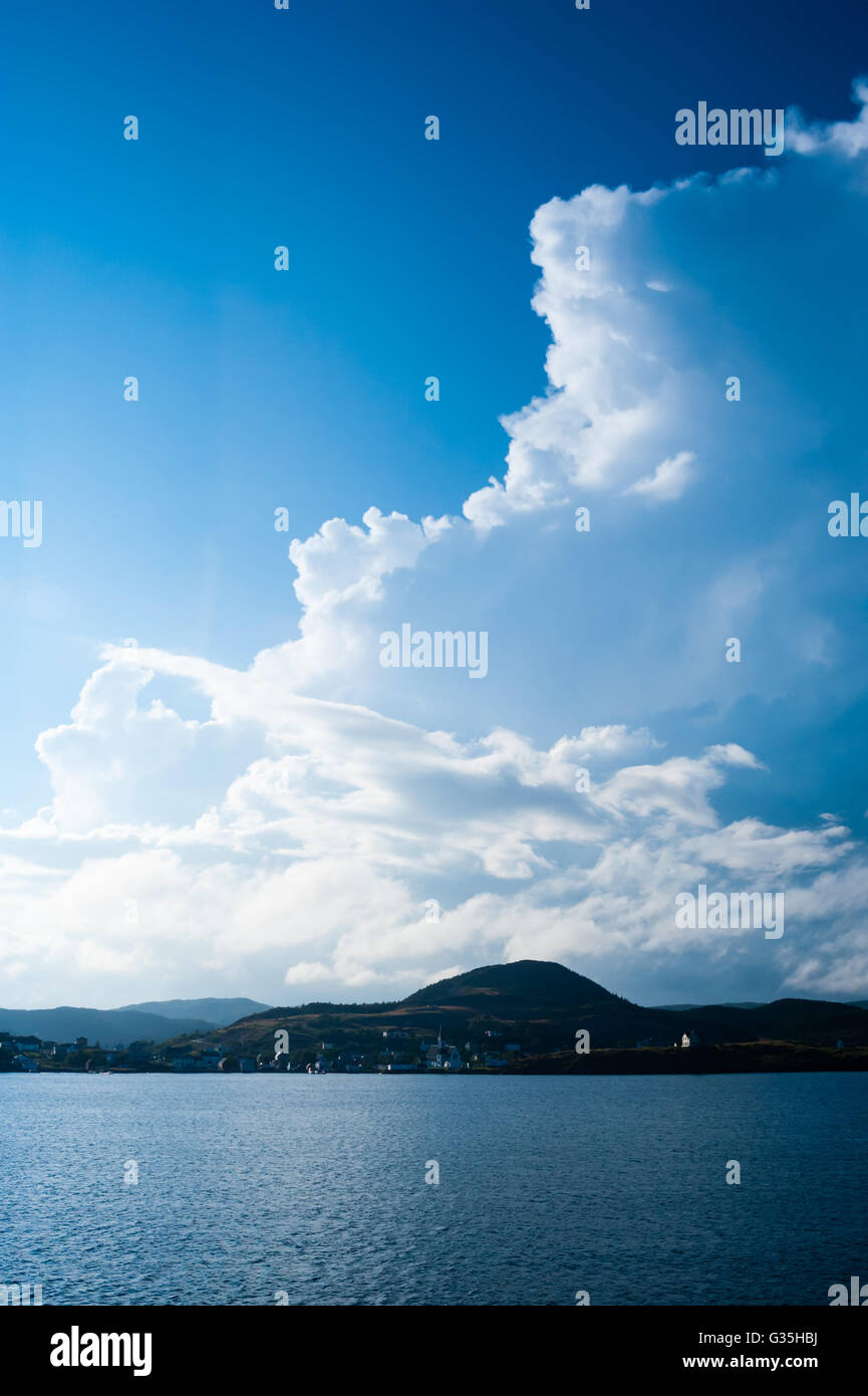 Grande fuga di nuvole sul cielo blu sopra villaggio sulla costa collinare, vicino a Trinità, Terranova, Canada. Foto Stock