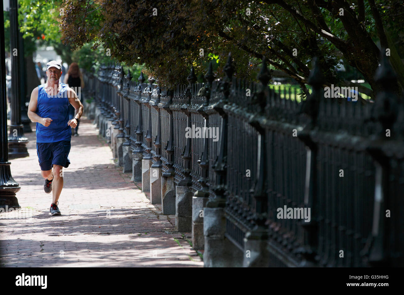 Uomo di jogging sul marciapiede accanto al giardino pubblico, Boston, Massachusetts, STATI UNITI D'AMERICA Foto Stock