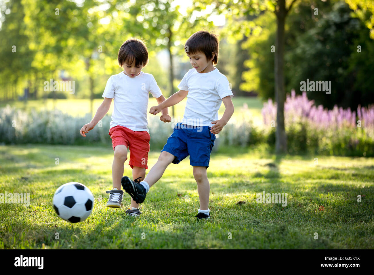 Due graziosi bimbi piccoli, giocando a calcio insieme, per la stagione  estiva. I bambini giocano a calcio per esterno Foto stock - Alamy